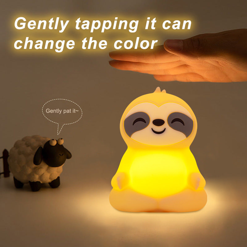 A hand tapping the top of the sloth light to change its color