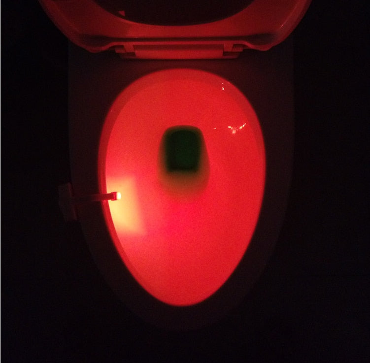 Toilet bowl lit red by the sensor light clipped to the rim