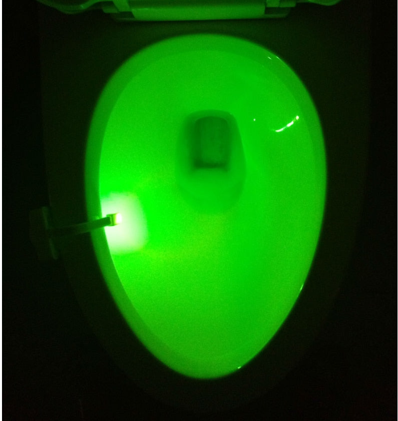 Toilet bowl lit green by the sensor light clipped to the rim