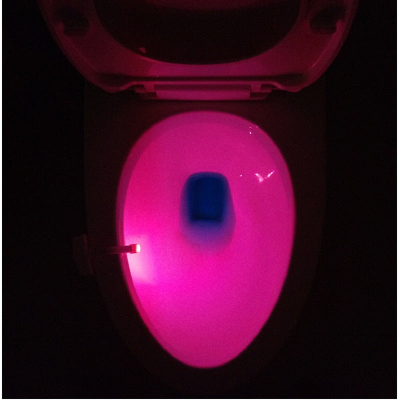 Toilet bowl lit deep pink by the sensor light clipped to the rim