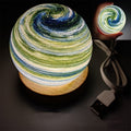 Planet night light in Aurora, a marbled glass globe lit warm on a wooden base