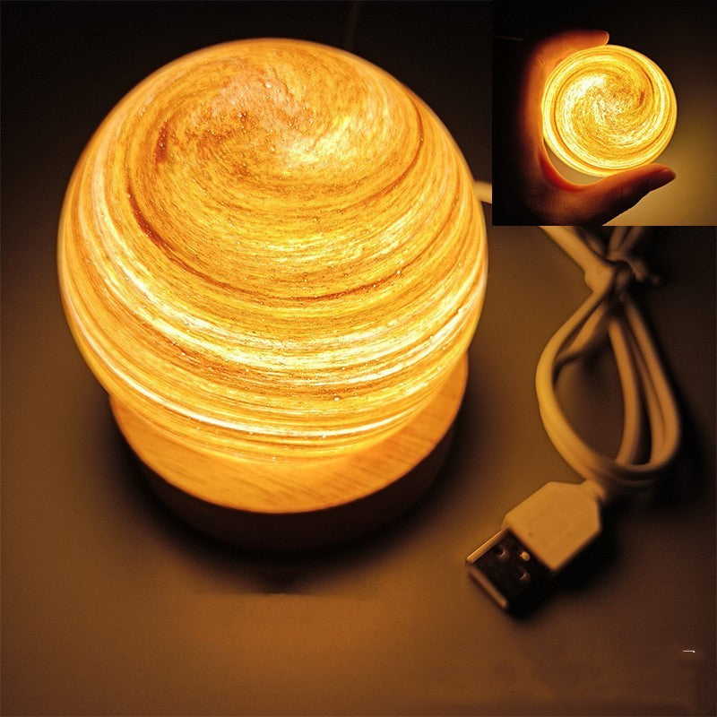 Planet night light in Sunset, a marbled glass globe lit warm on a wooden base
