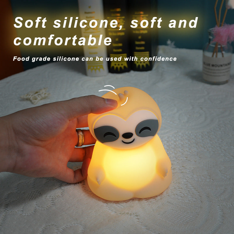 A hand holding the lit sloth light, showing the soft food grade silicone body