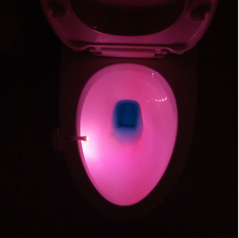 Toilet bowl lit soft pink by the sensor light clipped to the rim