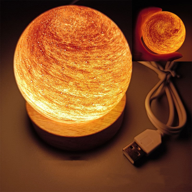 Planet night light in Rising Sun, a marbled glass globe lit warm on a wooden base