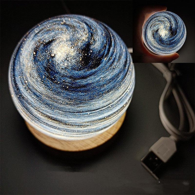 Planet night light in Starry Sky, a marbled glass globe lit warm on a wooden base