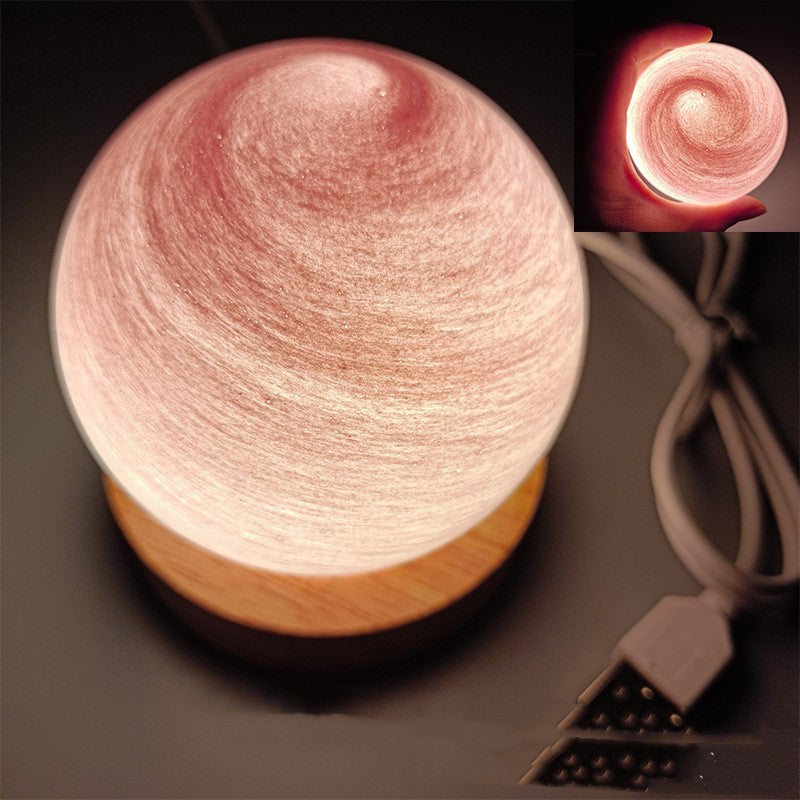 Planet night light in Blush Pink, a marbled glass globe lit warm on a wooden base