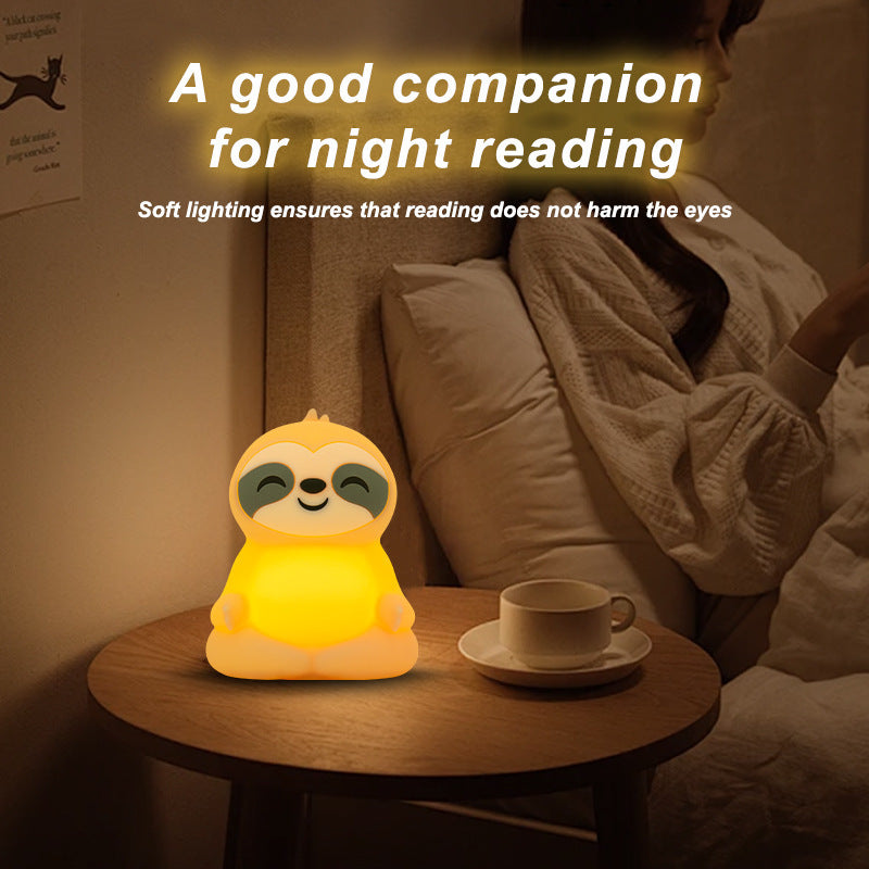 The sloth light on a bedside table beside a cup, lighting a book at night