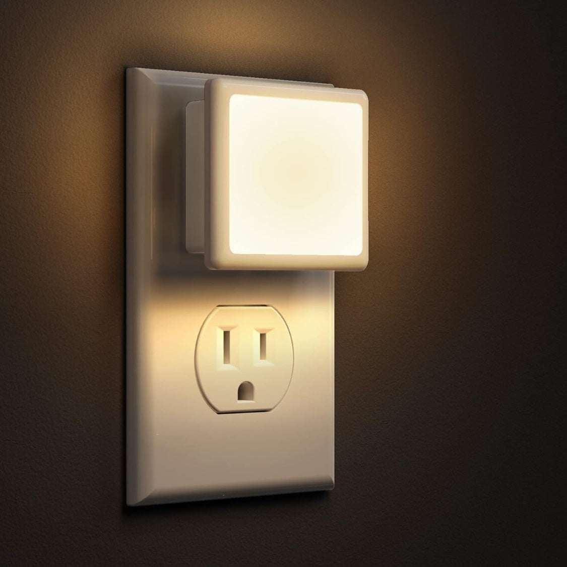 Close-up of the square night light plugged into a standard US wall outlet